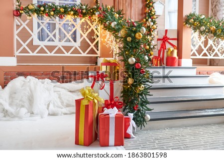 
New Year's decor. Brown gold verandah with a garland with red and gold balls. Great gifts, sledges and skates. Decorative lanterns with candles