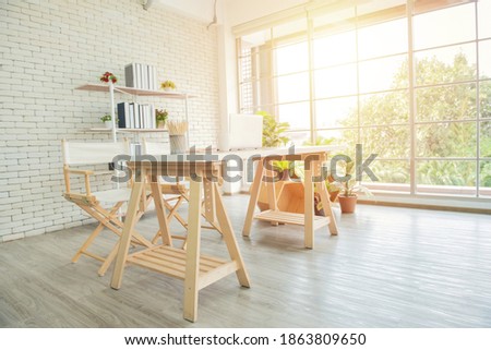 Brown wooden floor between pouf and grey sofa in white home office interior with chair at desk. Real photo