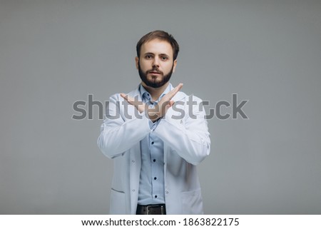 Doctor in protective mask showing stop gesture on white background. Prevent spreading of coronavirus.