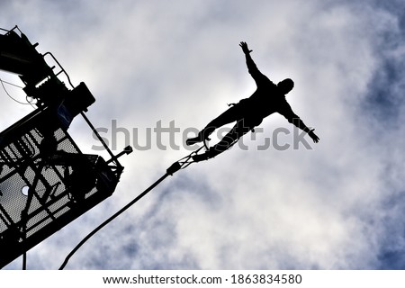Silhouette of bungee jumper from underneath Royalty-Free Stock Photo #1863834580