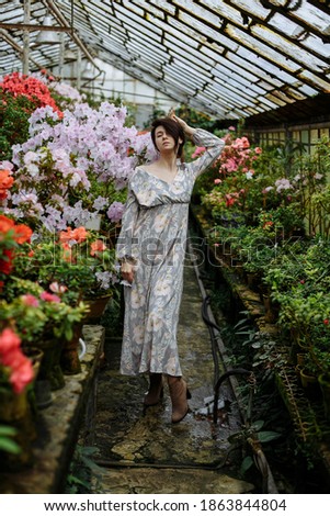 girl in a long dress in a greenhouse with azaleas