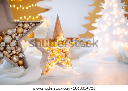 Big Christmas stars are decorated with golden balls and garlands. Decorative wooden Christmas tree Christmas gold and white on a white background