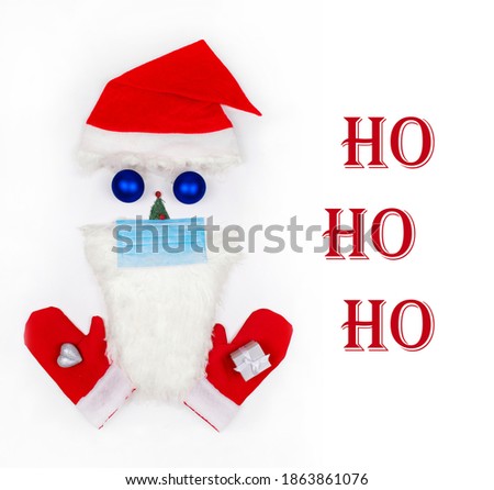 Christmas Ho Ho Ho greeting card. Santa Claus face made of Christmas toys, fir tree, beard in a medical protective mask with Santa's mittens on white background. Christmas symbol. Creative. Flat lay.
