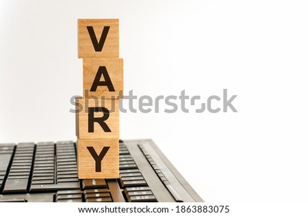 Concept image a wooden block and word - VARY - on white background. The cubes are located on the keyboard. Selective focus. Vary word made with building blocks isolated on white