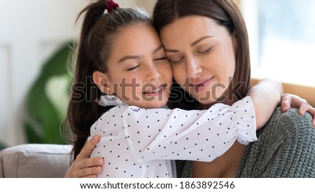 Close up of cute little girl hug cuddle young Caucasian mother feel grateful and thankful. Happy mom and small daughter embrace show love and care in relations, reconcile make peace after fight. Royalty-Free Stock Photo #1863892546