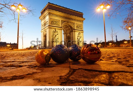 The famous Triumphal Arch at night and Christmas baubles in the background . Paris. France.