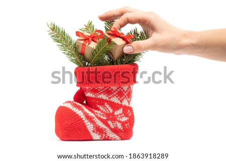 female hand lays down Little gifts with fir branches in Santa's boot
