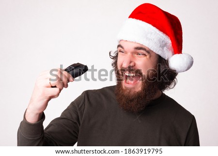 Surprised funny amazed bearded man wearing santa hat, holding a shaver, holidays promotions, dicounts