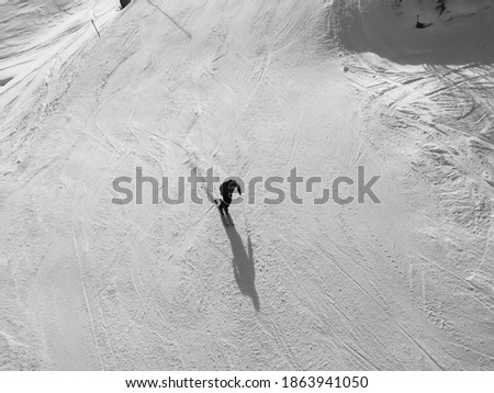 Lonely skier on the mountain skiing with his shadow down the swiss alps