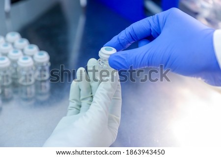Hand with medical glove holding a bottle vaccine from ice storage. Medication treatment at nitrogen freeze. Royalty-Free Stock Photo #1863943450