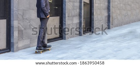 Feet of a confident business man with formal attire on riding a skateboard over city footpath