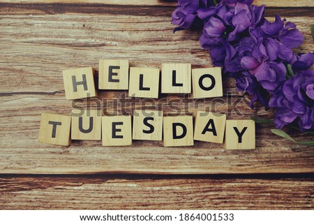 Hello Tuesday alphabet letter with Blooming flower on wooden background