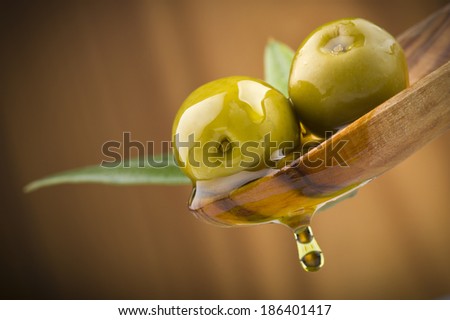 Two olives and leaves with drop oil on wood spoon 