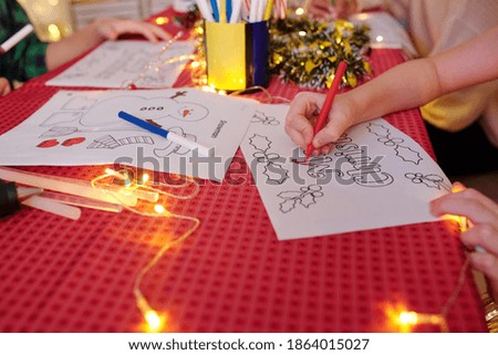 Close-up image of kids coloring Christmas pictures for celebration