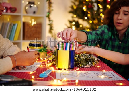 Children taking felt pens from cup when coloring pictures for home Christmas party
