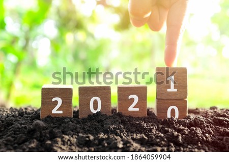 Male hand bury year 2020 to change to 2021 in wooden blocks cubes. New year, hello and goodbye concept. Royalty-Free Stock Photo #1864059904