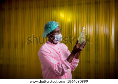 Worker of science in bottle beverage factory wearing safety  hat and face mask show working to check quality of Basil seed produce on conveyer belt before distribution to market business