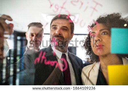 Businesspeople planning on a glass wall Royalty-Free Stock Photo #1864109236