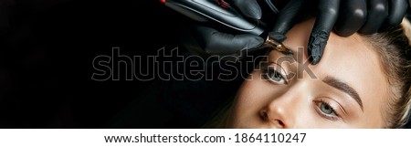 Beauty specialist doing eyebrow powder permanent makeup on a female brows. Space for text. Negative space Royalty-Free Stock Photo #1864110247