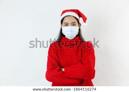 Asian beautiful woman posing in red dress and santa hat wearing medical face mask to protect from covid-19 and coronavirus. Girl with black long hair on white background