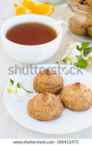 Fresh homemade nut cookies with orange and flowers on a wooden table