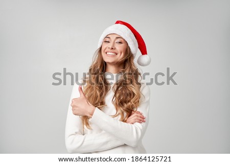 Woman christmas Santa Hat sweater white studio background Beautiful caucasian female curly hair portrait Happy person positive emotion Holiday concept Teeth smile Thumbs up gesture Advertising banner