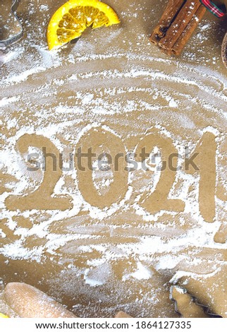 The 2021 text is written on flour among Christmas decorations and Christmas tree branches