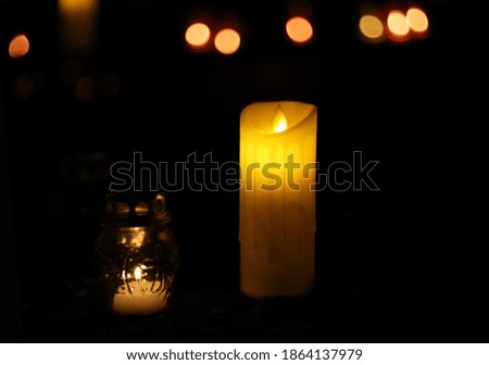 Candles and lamps burn on the granite of the monument on a dark night during a memorial ceremony