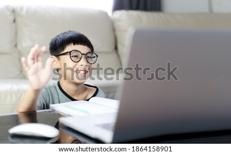 asian boy is using a laptop and communicates on the Internet at home.smile boy is using a laptop and study online with video call teacher at home. homeschooling, distant learning