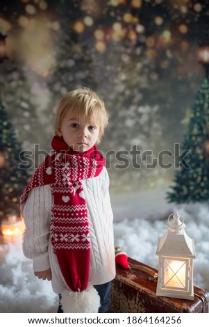 Littlw toddler child with suitcase and little gingerman toy in hand, walking in a snowy forest, christmas theme picture