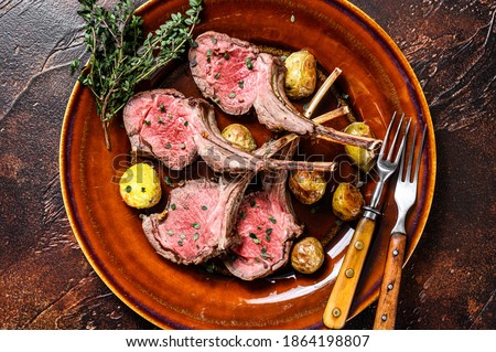 Roasted lamb meat rib chop steaks with potato. Dark background. Top view. Royalty-Free Stock Photo #1864198807