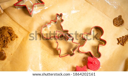 Red ginger bread shapes and dough laying on brown baking paper. Baking gingerbread.
