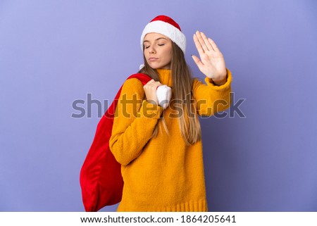 Lithianian woman with christmas hat isolated on purple background making stop gesture and disappointed