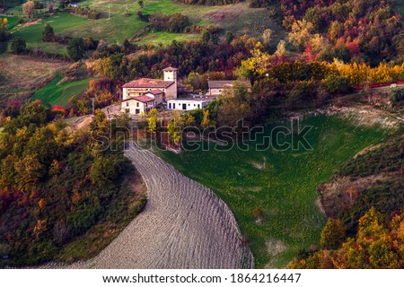 Scenic view of italian countryside village against autumn foliage during sunset, Grassano Basso church, Reggio Emilia, Italy