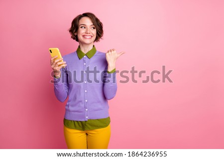 Photo of pretty lady hold telephone direct finger empty space wear purple jumper pants isolated pink color background