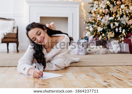 Lady in the New Year's interior. woman writes with a pen on a white sheet of paper. Christmas concept. High quality photo