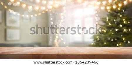 A wood table, tabletop product display with a festive Christmas background of Christmas tree and fairy lights.