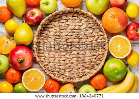 Fresh fruits background. Food photography different fruits and empty wicker tray on wooden white background.Flat lay.
