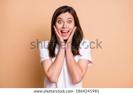 Photo portrait of amazed shocked cheerful girl touching cheeks with hands smiling isolated pastel beige color background