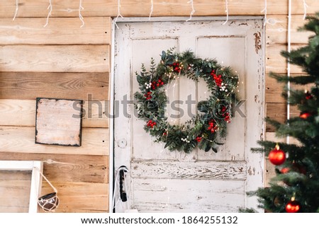 Wooden white door to the house decorated with Christmas wreath.