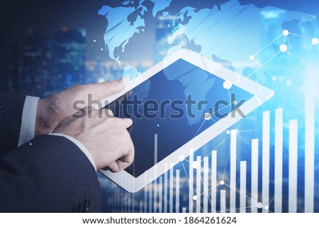 Hands of businessman using tablet in blurry city with double exposure of world map and graph. Toned image. Elements of this image furnished by NASA