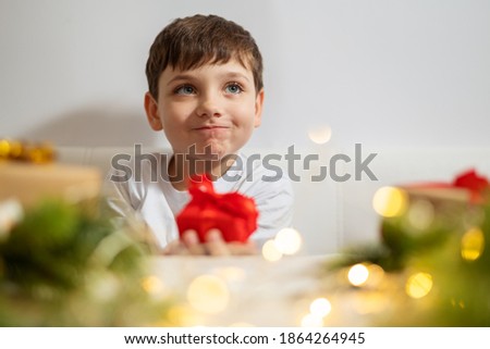 Cute little kid boy at christmas giving a red present box. Xmas holiday concept with copy space