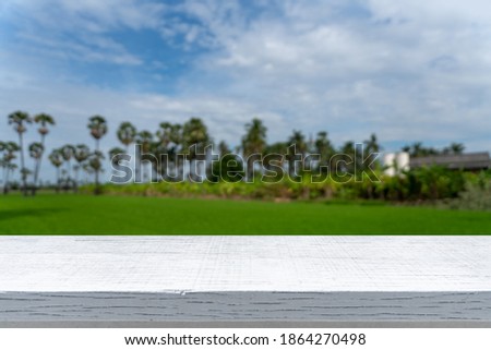 Picture of a white wooden table for editing and placing items  And the background is a view of green rice fields with palm trees  Which is blurred