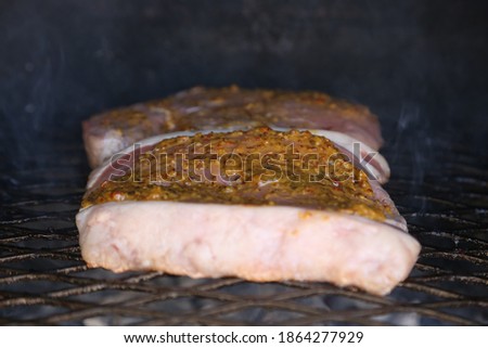 A rump steak with mustard basting sauce being cooked on a braai in South Africa. This photo has selective focus.  
