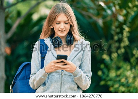 Beautiful caucasian student teenager smiling happy using smartphone at the park