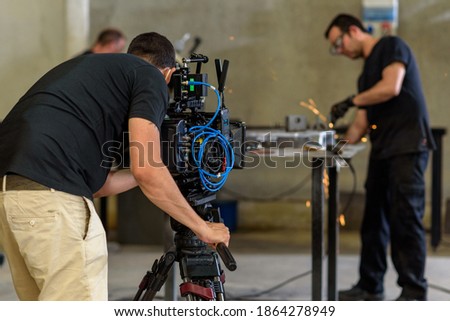 Cameraman with digital film camera in industrial steelworks