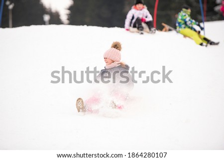 Little girl in bob-sleigh enjoying winter time.