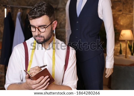 Cute male fashion designer taking notes