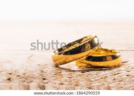 Two golden wedding rings on wooden background with copy space for text