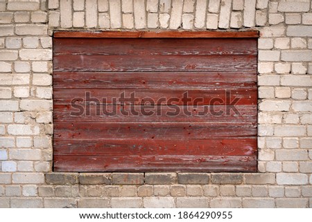 Old wooden noticeboard on the brick wall.  Empty rectangular frame for text, images and ads. 